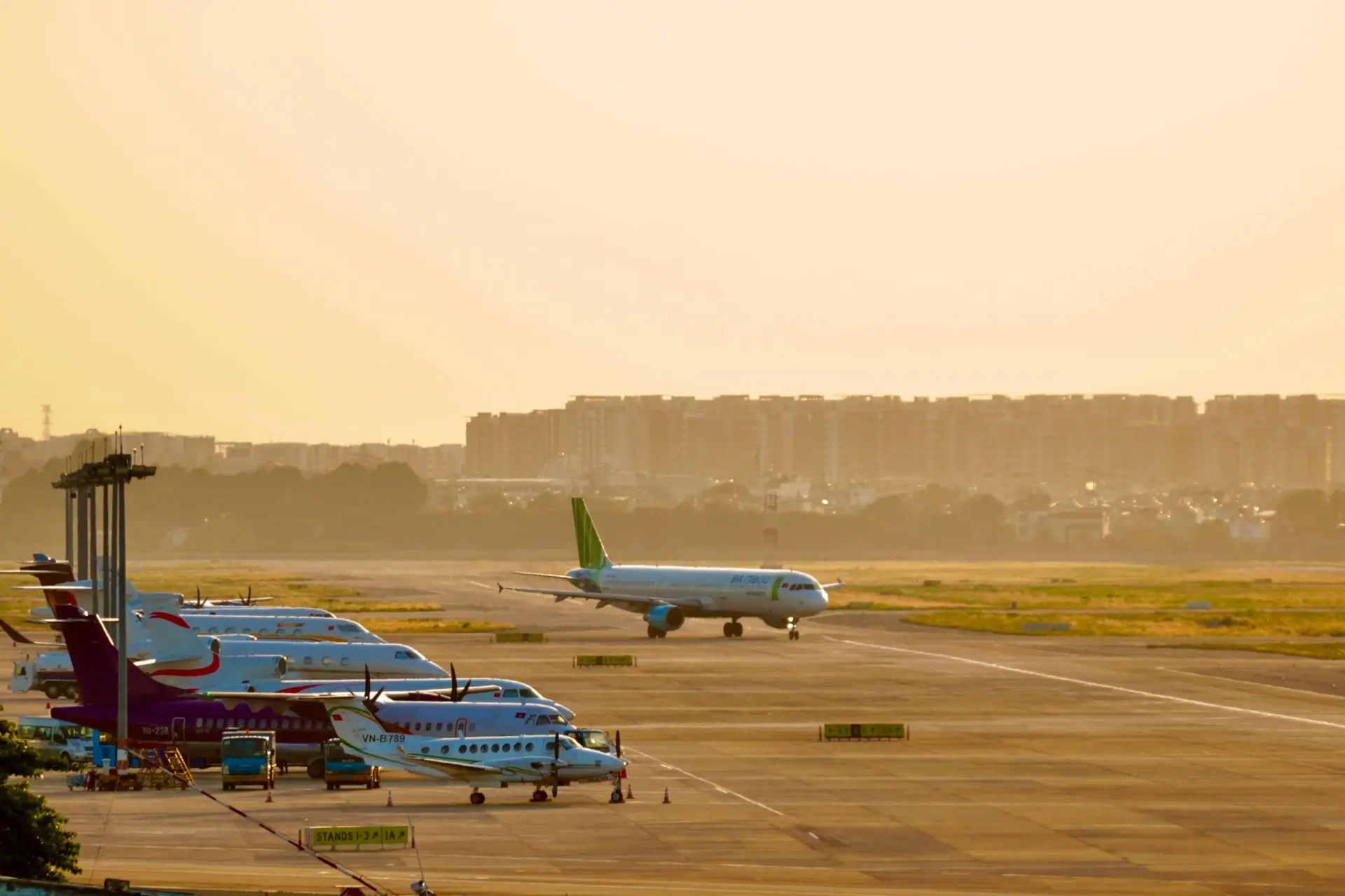 Airplanes parked on a runway during sunrise, capturing a busy airport scene.