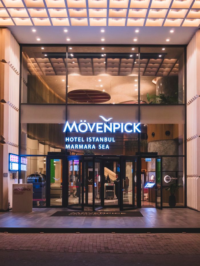 Night view of Mövenpick Hotel Istanbul Marmara Sea entrance with illuminated signage and glass facade.